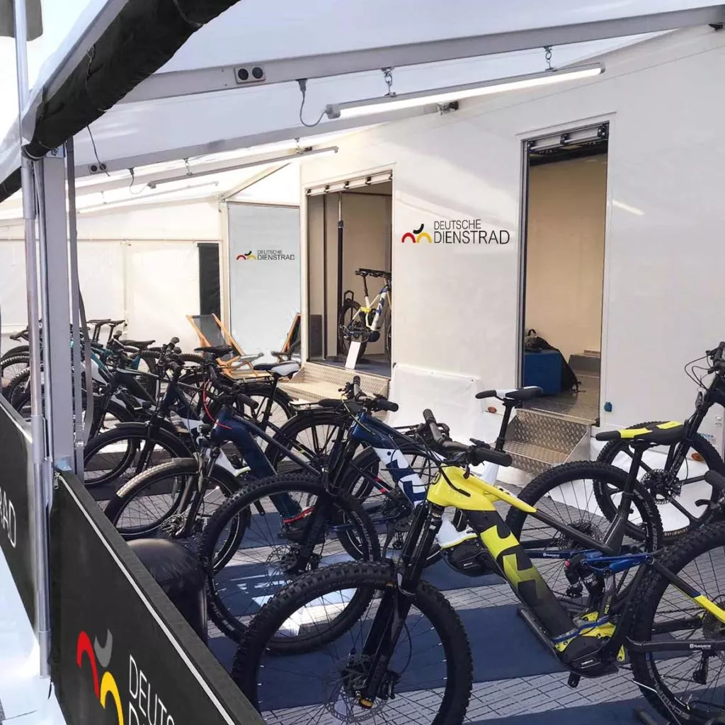 Several e-bikes are displayed in a tent with the "Deutsche company bike" logo on the wall.